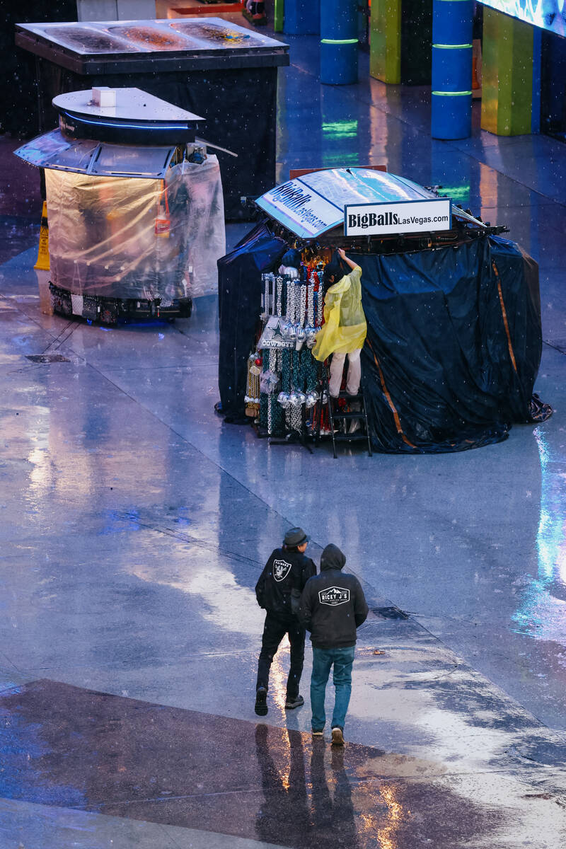 Pedestrians walk in the rain on Tuesday, Nov. 18, 2025 at the Fremont Street Experience in Las ...