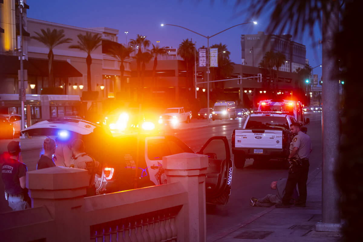 Metropolitan Police Department officers detain a man by a bus stop off Flamingo Road, outside o ...