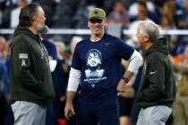 Dallas Cowboys head coach Brian Schottenheimer, center, chats with Raiders offensive line coach ...