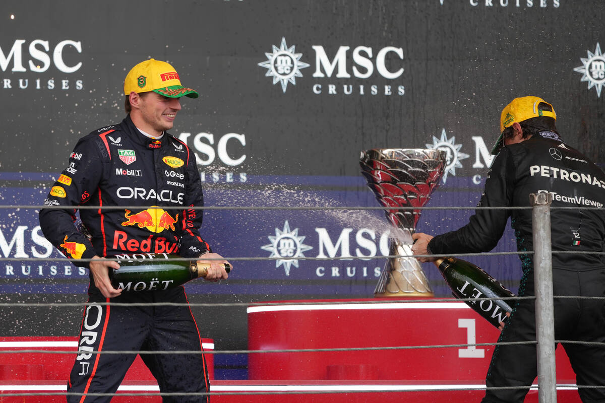 Red Bull driver Max Verstappen of the Netherlands, left, sprays champagne to Mercedes driver Ki ...