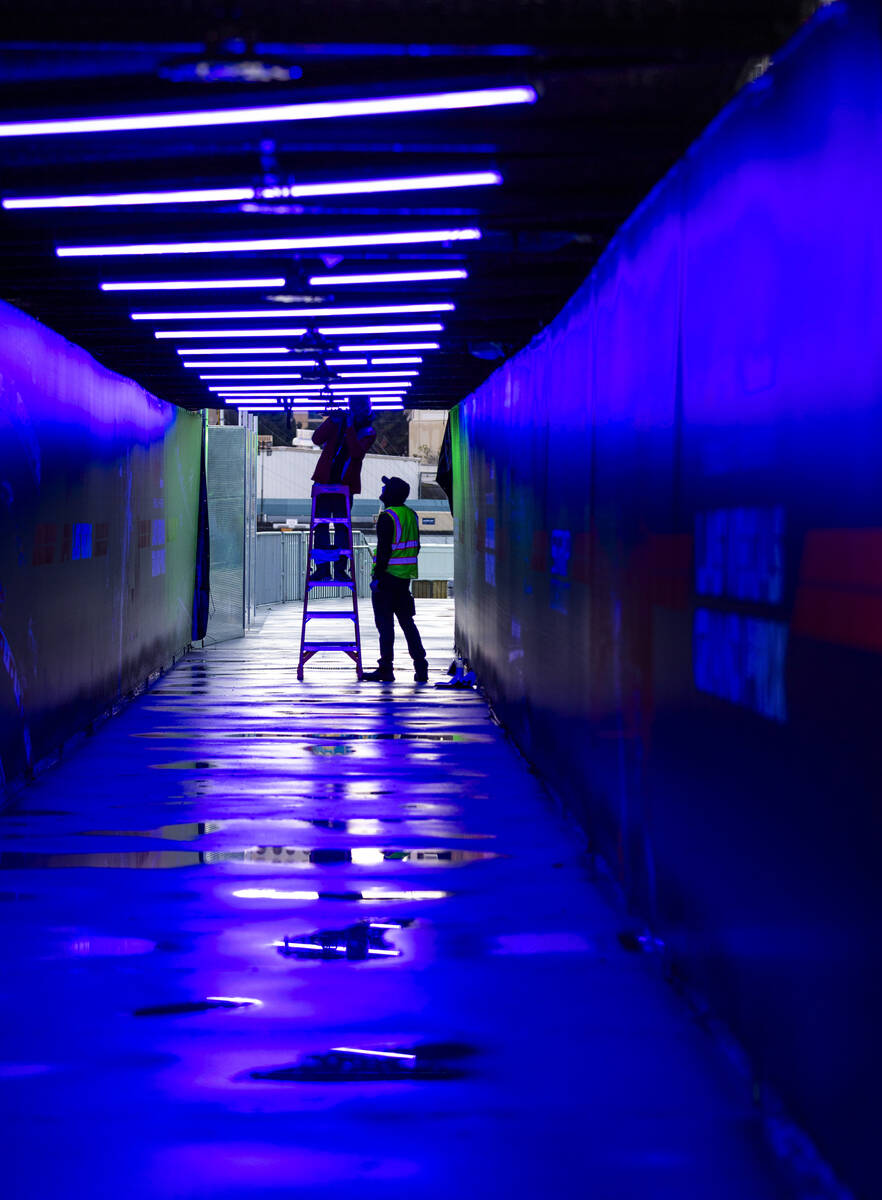 Crew members work on lighting within a pedestrian bridge at the Las Vegas Grand Prix on Wednesd ...