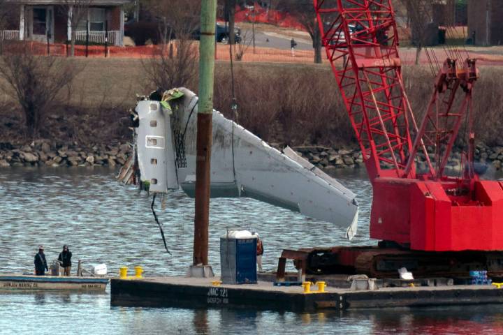 Rescue and salvage crews pull up airplane wreckage of an American Airlines jet in the Potomac R ...