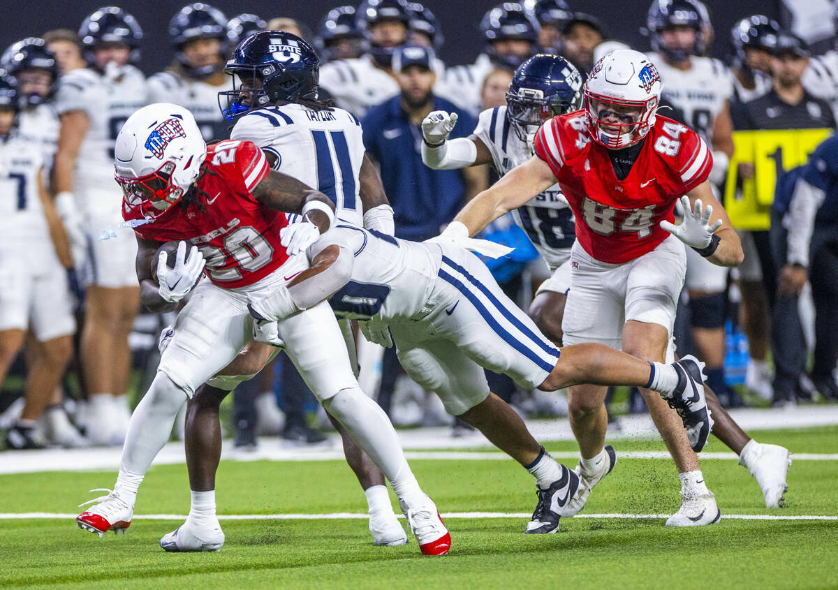 UNLV running back Jaylon Glover (20) battles for more yards with Utah State Aggies defensive en ...