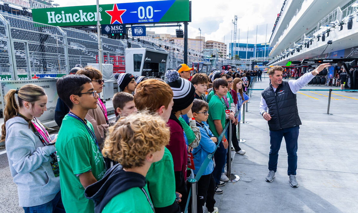 Students learn about Formula One cars from a Aston Martin team representative during a communit ...