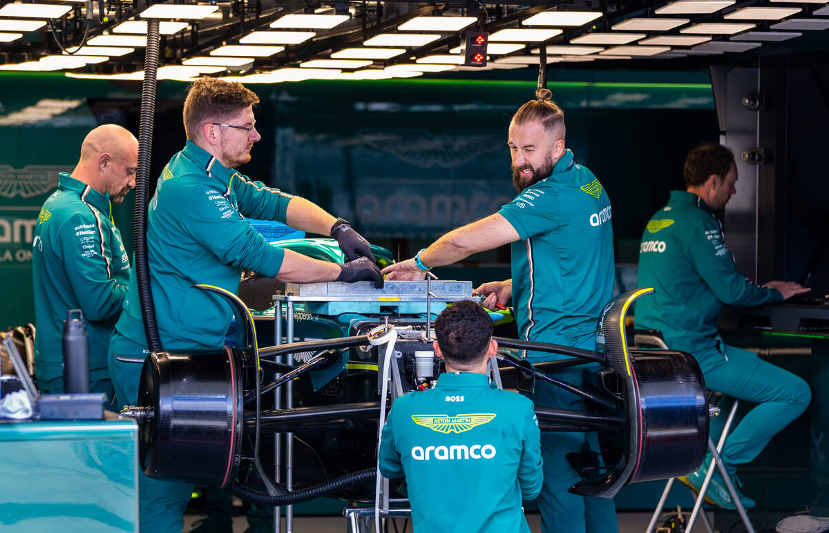 A crew from Lance Stroll's Aston Martin F1 Team bay works on his race car during a communi ...