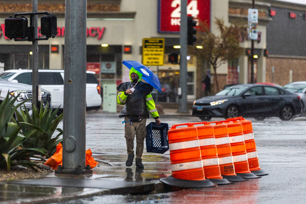 A person with an umbrella walks along Paradise Road as moderate to heavy rain moves through the ...