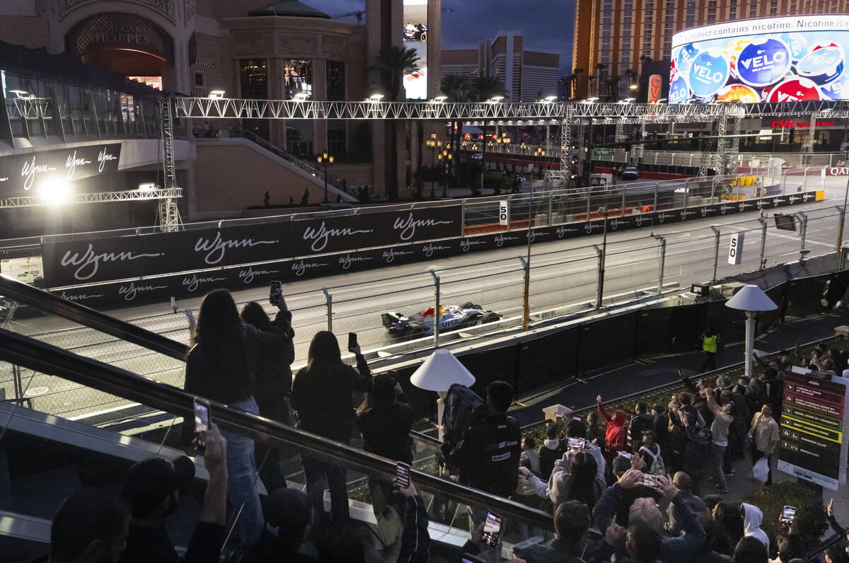 People watch and record the first practice of the Formula One Las Vegas Grand Prix auto race al ...