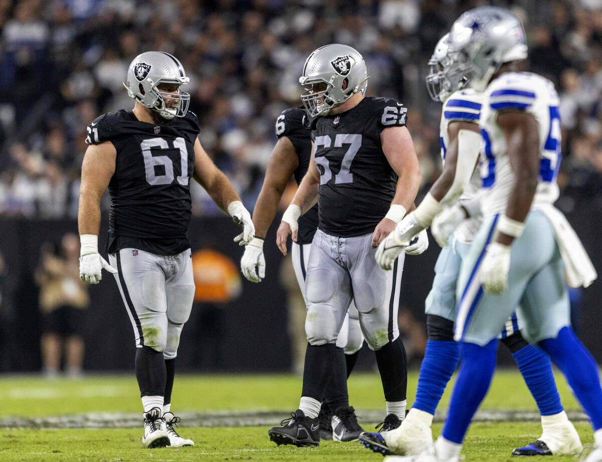 Raiders guard Jordan Meredith (61) speaks with Raiders center Will Putnam (67) between plays du ...