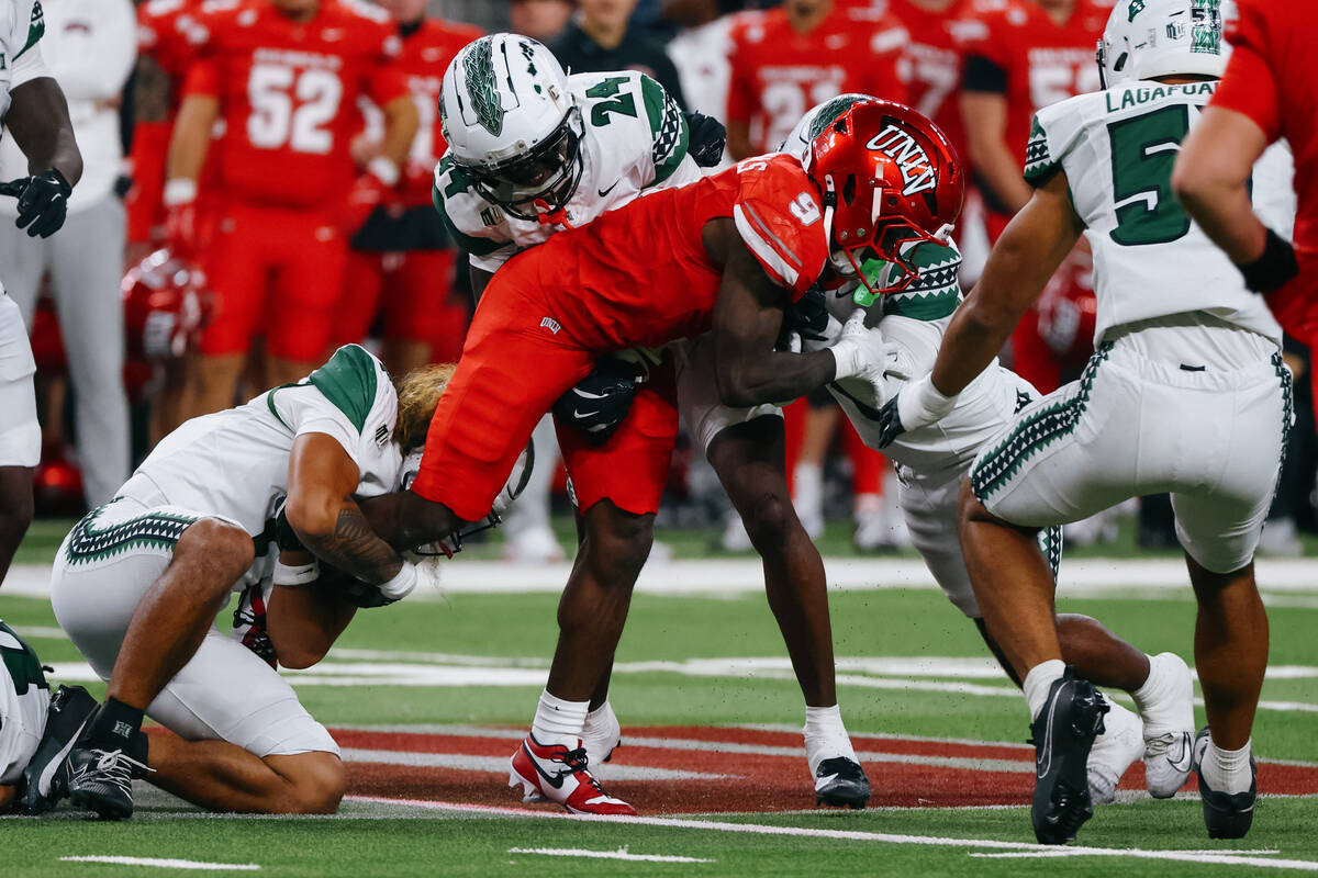 Hawaii defenders tackle UNLV running back Jai'Den Thomas (9) during the first half of the ...