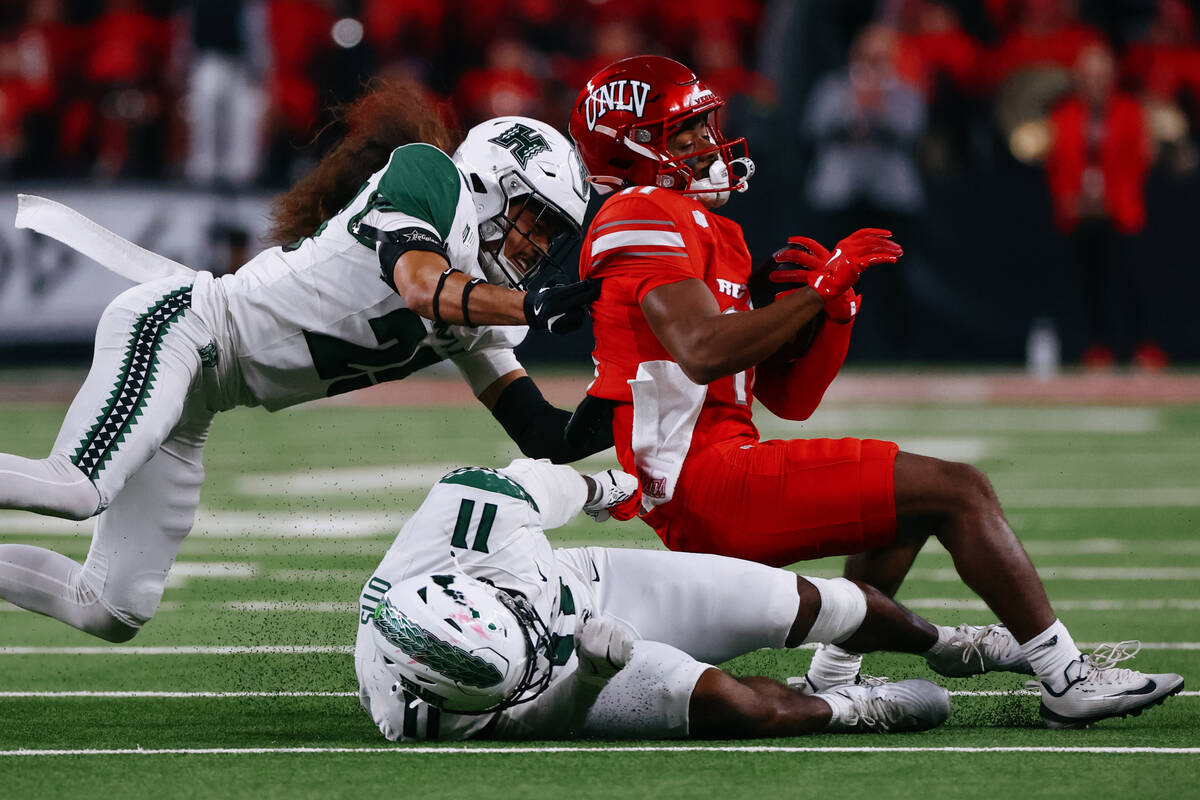 Hawaii defensive back Matagi Thompson (25) and Hawaii linebacker Jamih Otis (11) tackle UNLV wi ...