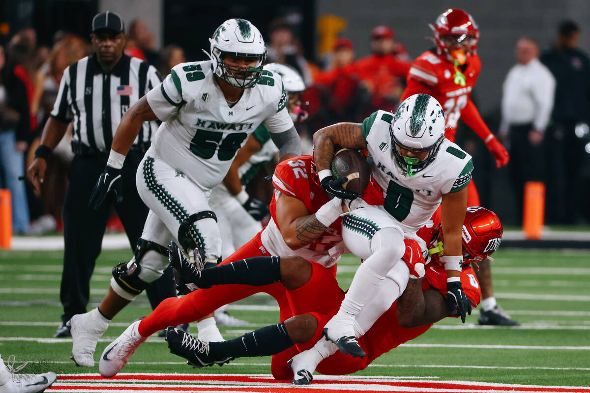 UNLV defensive end Kenji Scanlan (32) and UNLV linebacker Marsel McDuffie (8) take down Hawaii ...