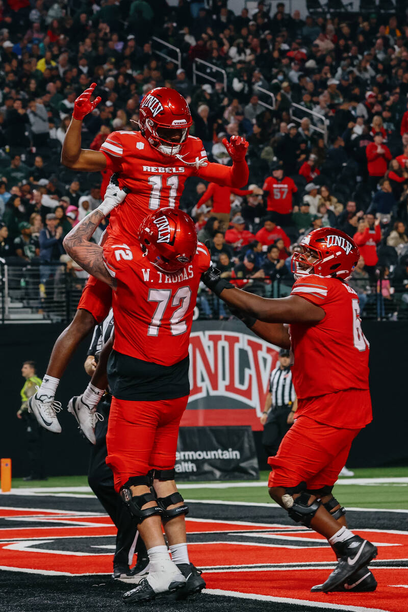 UNLV offensive lineman Will Thomas (72) lifts up teammate UNLV wide receiver JoJo Earle (11) af ...