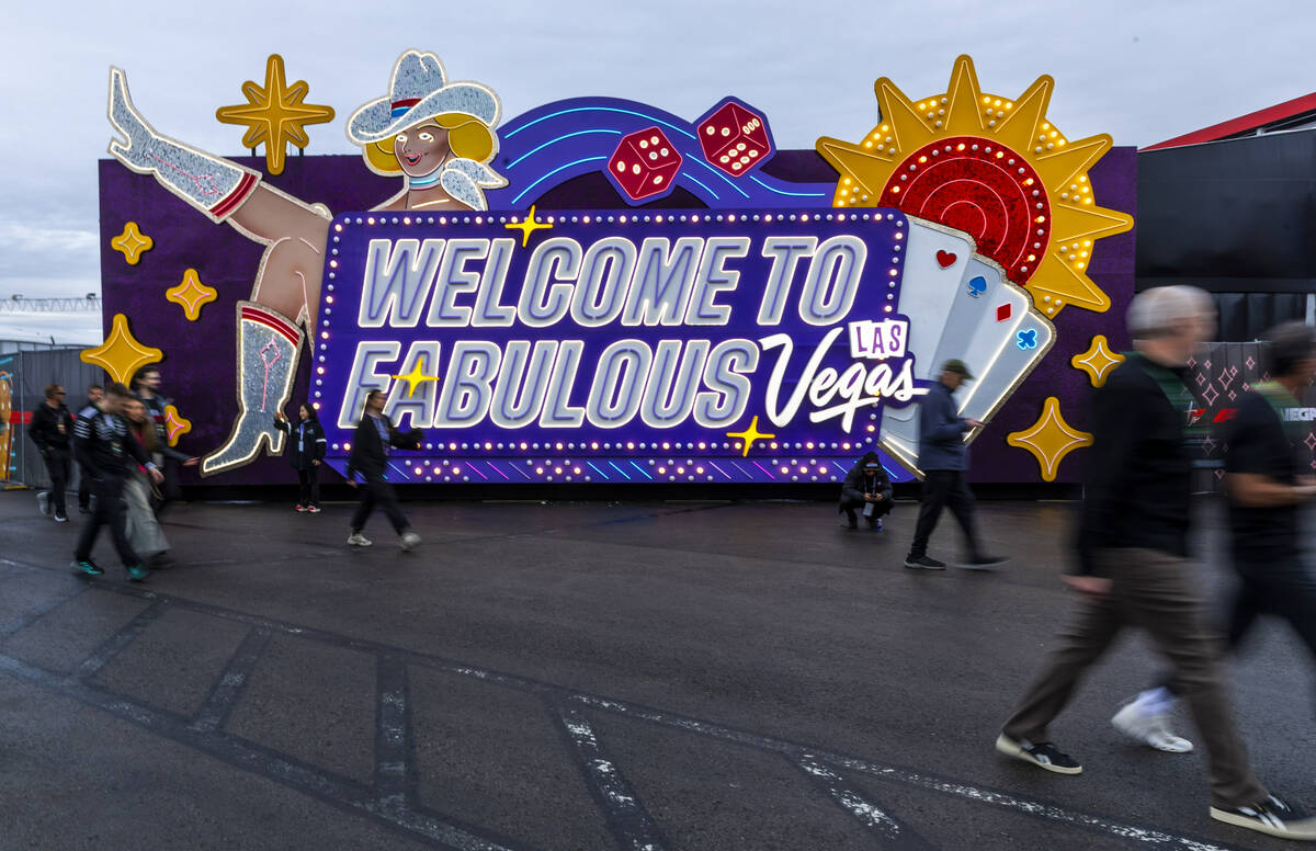 Fans make their way past a "Welcome to Fabulous Las Vegas" near the F1 Pit Building f ...