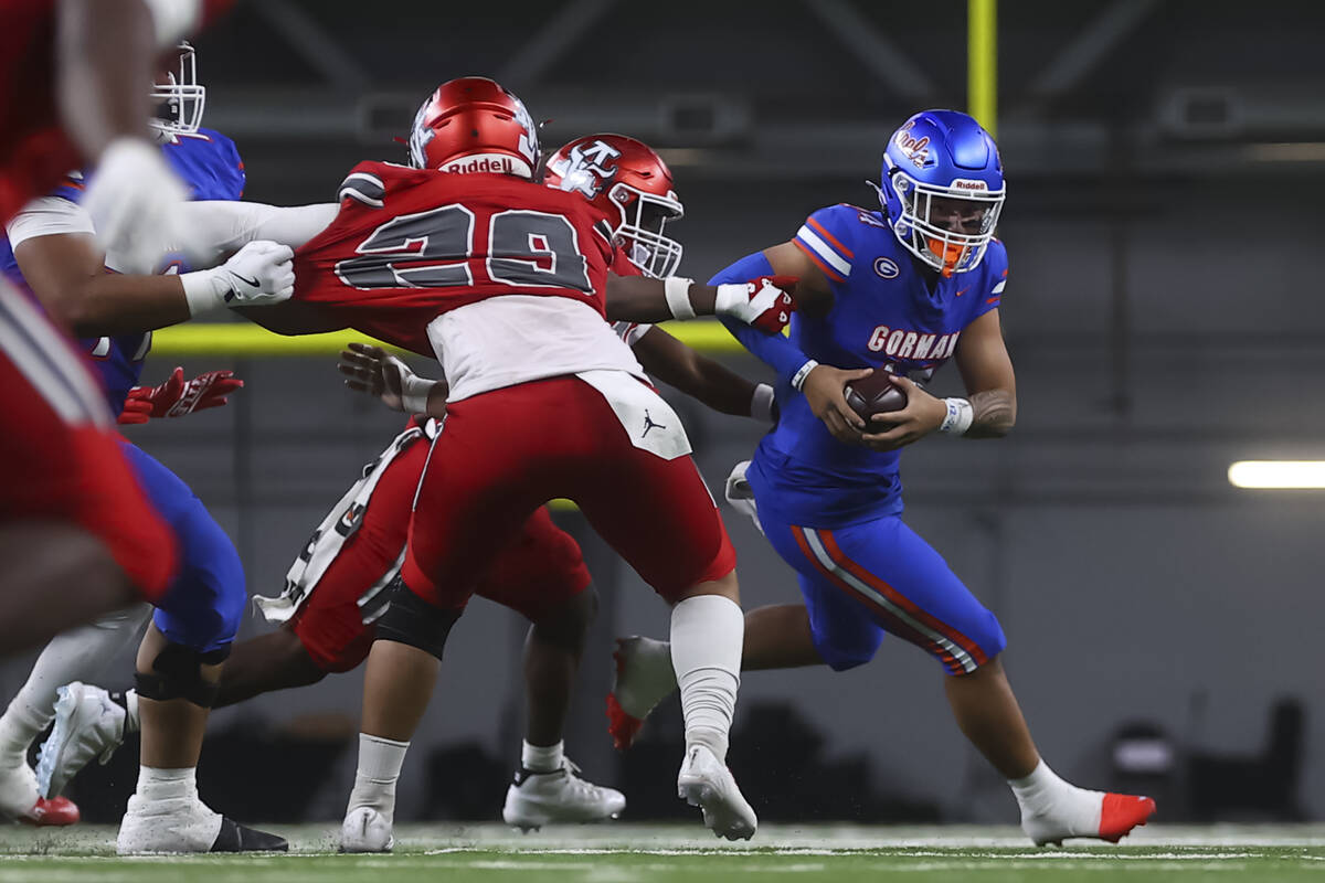 Bishop Gorman quarterback Maika Eugenio (14) tries to escape Arbor View defenders during first ...