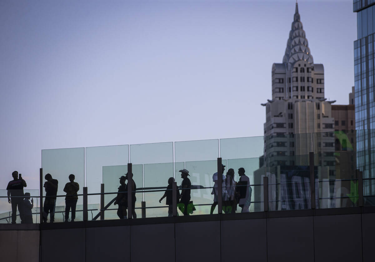 People cross a pedestrian bridge along the Las Vegas Strip during Labor Day weekend on Sunday, ...