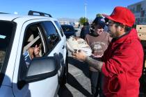 Volunteer Jacob Arbes delivers a turkey to a driver during a turkey giveaway sponsored by Three ...