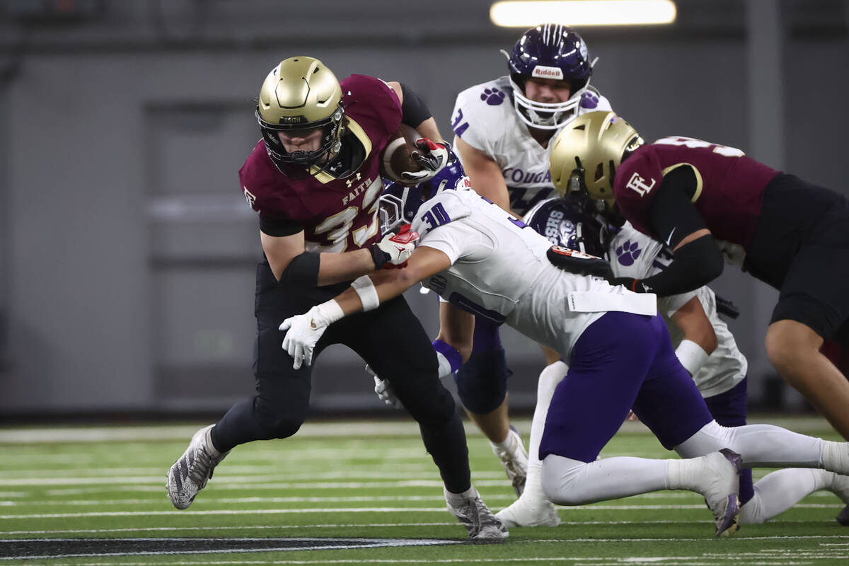 Faith Lutheran running back Justin Robbins (33) gets stopped by Spanish Springs’ Marian ...