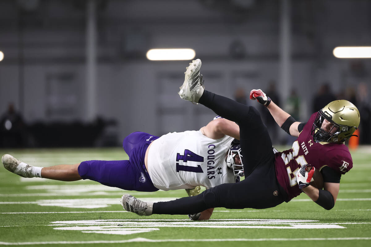 Faith Lutheran running back Justin Robbins (33) gets tackled by Spanish Springs middle lineback ...
