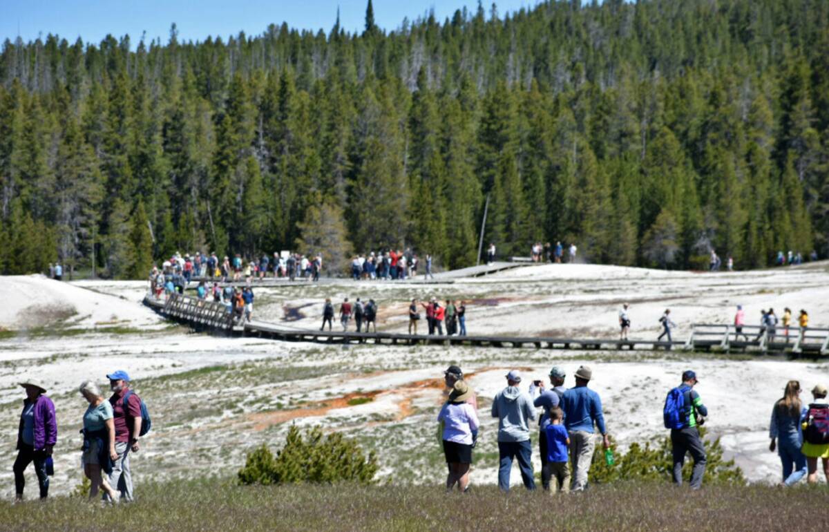 Tourists walk along a boardwalk in Upper Geyser Basin on June 22, 2022, in Yellowstone National ...