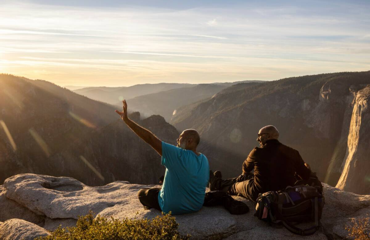 Visitors watch a sunset on rock ledge near Taft Point in Yosemite National Park, Calif., Oct. 3 ...