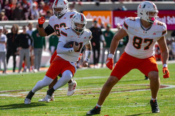 Miami quarterback Carson Beck (11) runs the ball behind tight end Alex Bauman (87) during the f ...