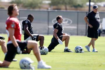 Raiders offensive coordinator Chip Kelly, right, watches team's stretch session during pra ...