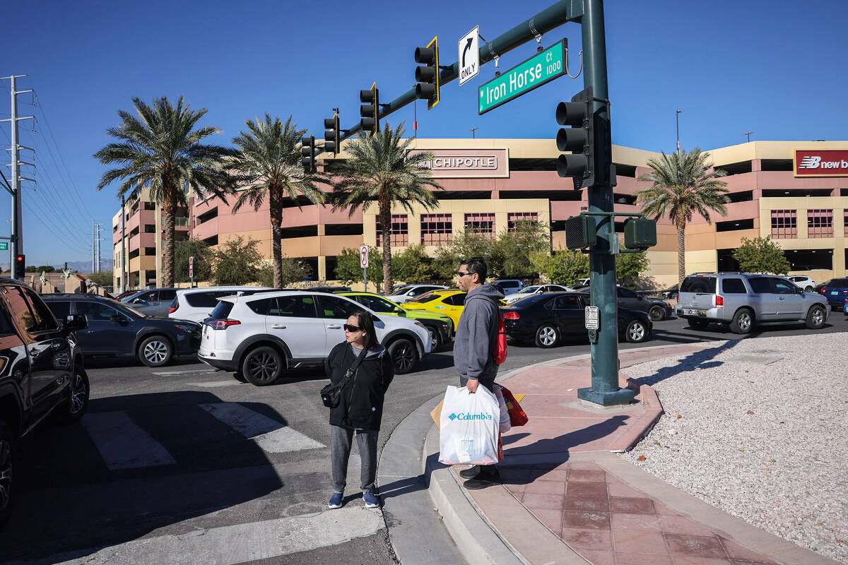 People wait to cross busy streets after finishing shopping during Black Friday at Las Vegas Nor ...