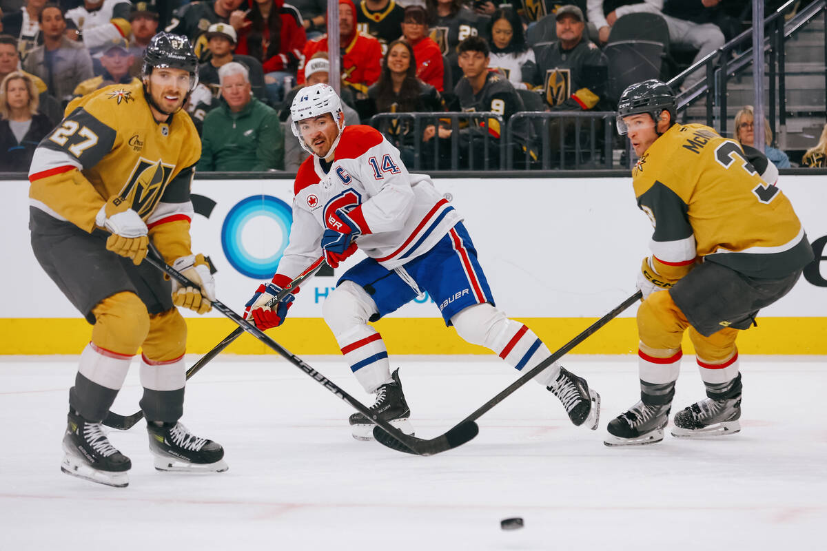 Montréal Canadiens center Nick Suzuki (14) passes the puck around Golden Knights defensema ...