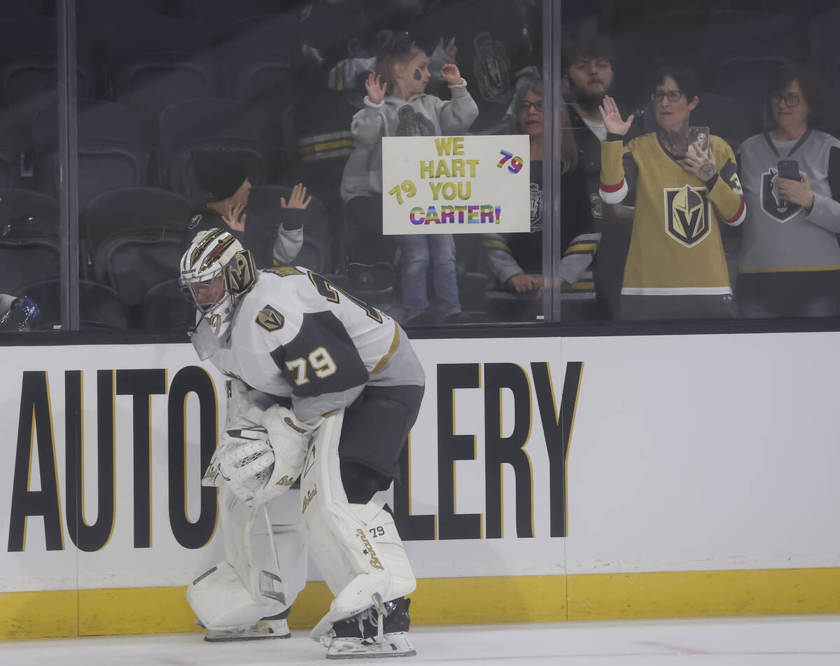 Silver Knights goaltender Carter Hart (79) warms up as a young fan holds up a sign in support b ...