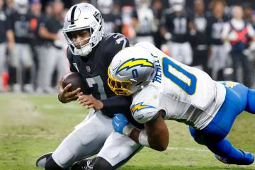 Raiders quarterback Geno Smith (7) is taken down by Los Angeles Chargers linebacker Daiyan Henl ...