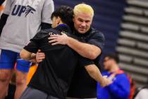 SLAM Academy wrestling coach Jake Rollans (facing) hugs SLAM wrestler Manuel Saldate as he acce ...