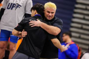 SLAM Academy wrestling coach Jake Rollans (facing) hugs SLAM wrestler Manuel Saldate as he acce ...