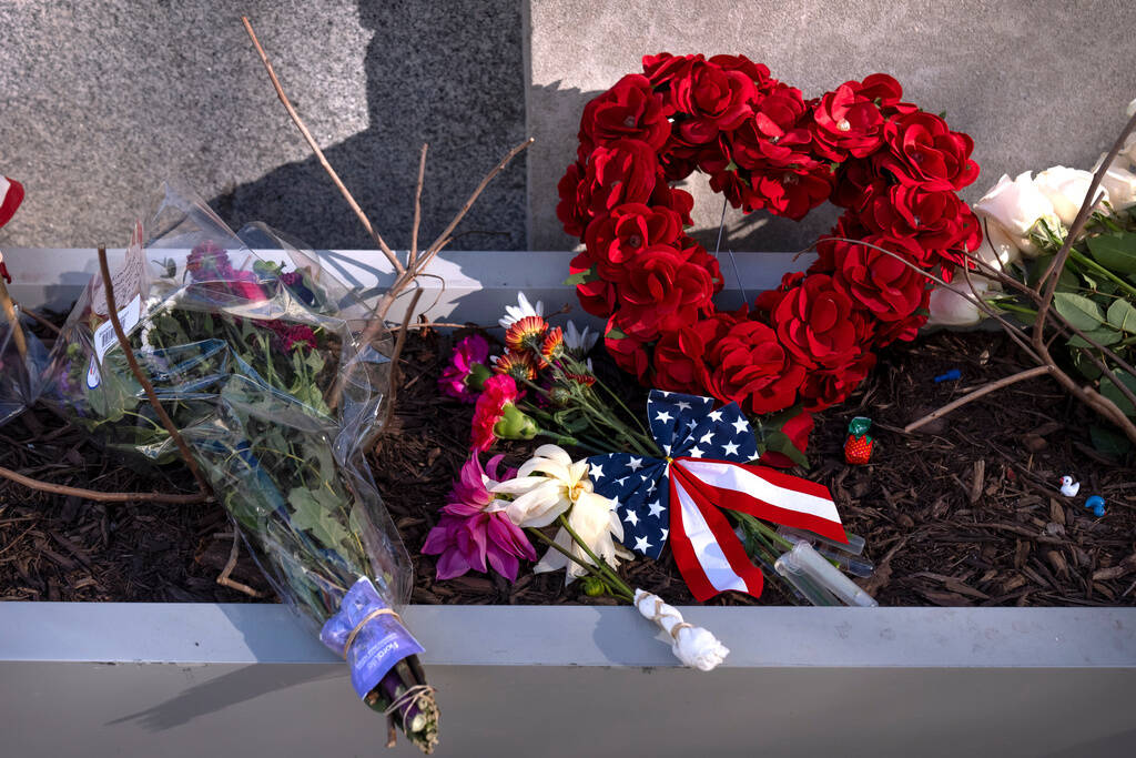A small memorial of flags, flowers, other items are seen in a planter, Friday, Nov. 28, 2025, n ...