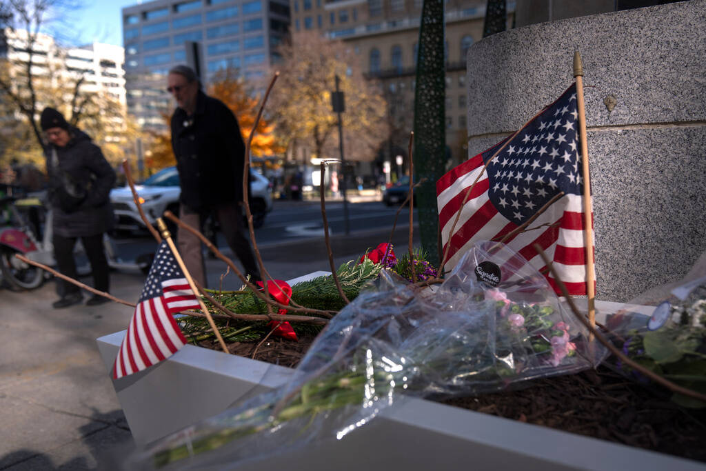 People walk past a small memorial in a planter, Friday, Nov. 28, 2025, near the site where two ...