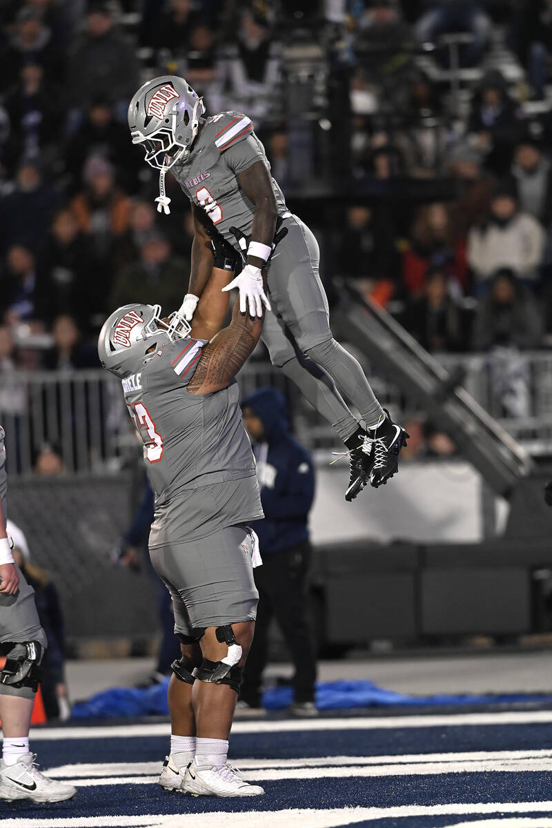 UNLV's Alani Makihele helps Jai'Den Thomas celebrate his touchdown against Nevada in the first ...