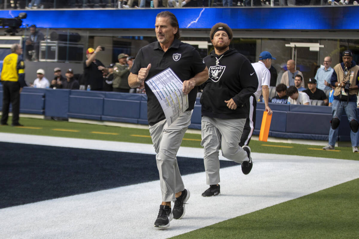 Raiders interim offensive coordinator Greg Olson makes his way to the field followed by assista ...