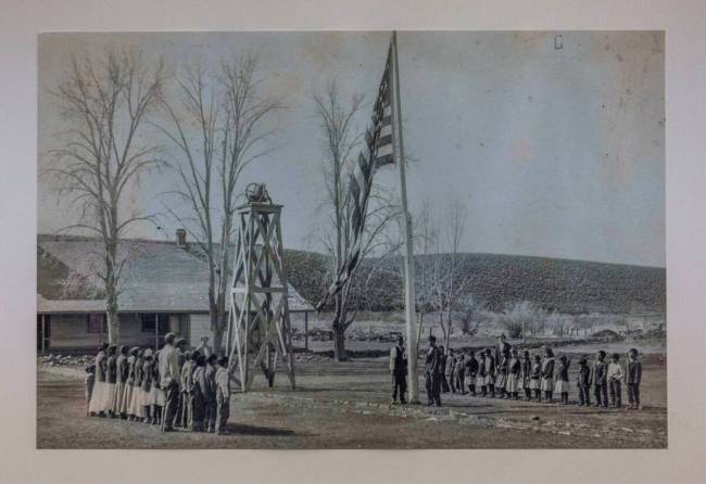 In a historic photo, Paiute-Shoshone are made to stand as the American flag is raised, part of ...