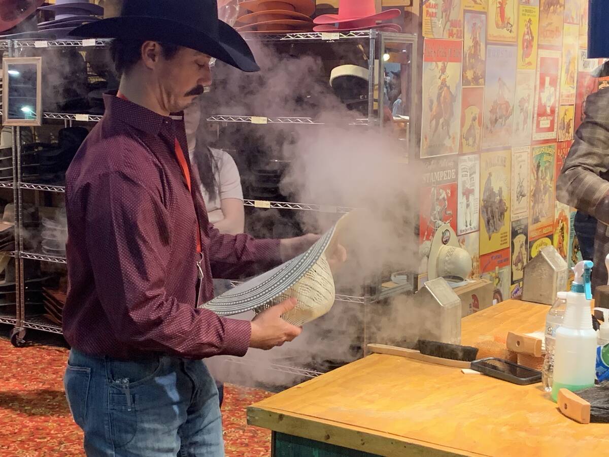A cowboy hatmaker plies his trade, steaming a hat into shape at Cowboy Christmas inside the Sou ...