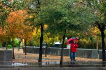 A woman takes a smoke break beneath an umbrella on the UNLV campus on Tuesday, Nov. 18, 2025, i ...