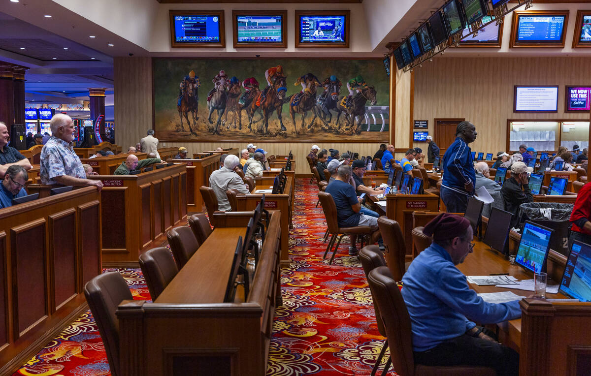 People place their bets and watch the multiple video screens in the sportsbook within the South ...