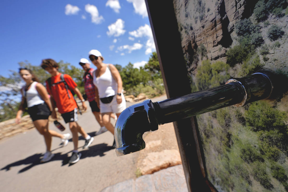 A group of day visitors walk past a closed water bottle tap along the Rim Trail on Thursday, Au ...