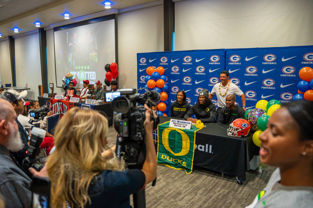 Jett Washington poses for a photo with his coach and family after signing his offer letter to p ...