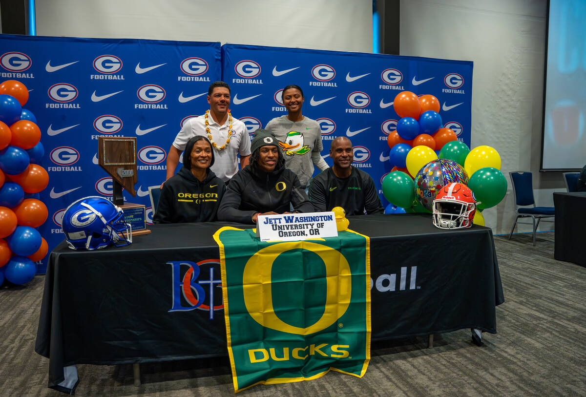 Jett Washington poses for a photo with his coach and family after signing his offer letter to p ...