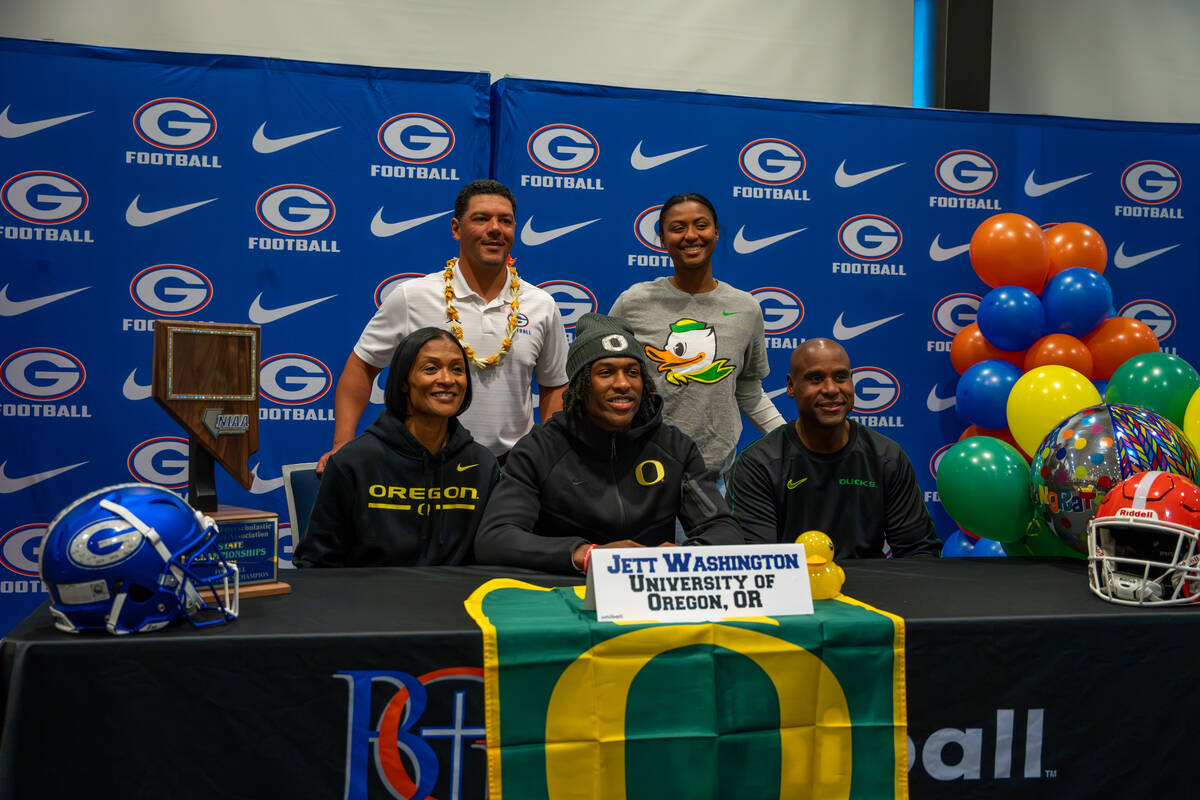 Jett Washington poses for a photo with his coach and family after signing his offer letter to p ...