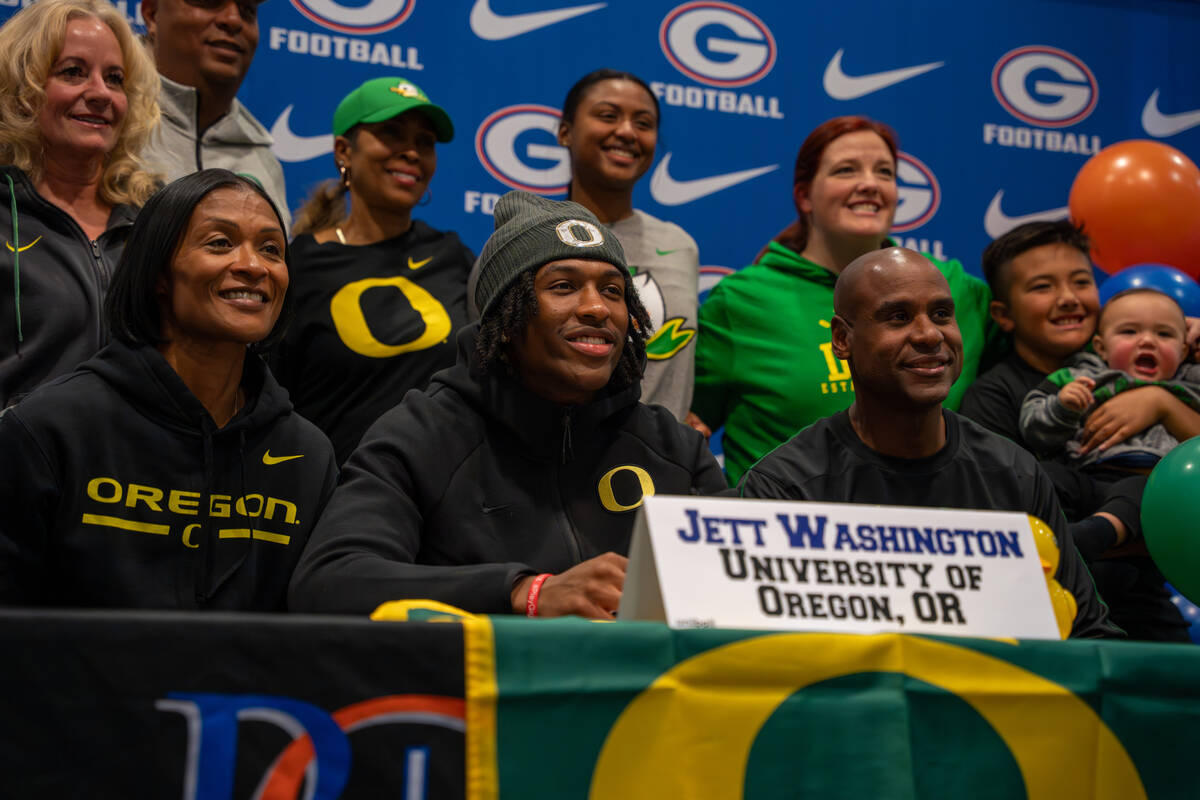 Jett Washington poses for a photo with his coach and family after signing his offer letter to p ...