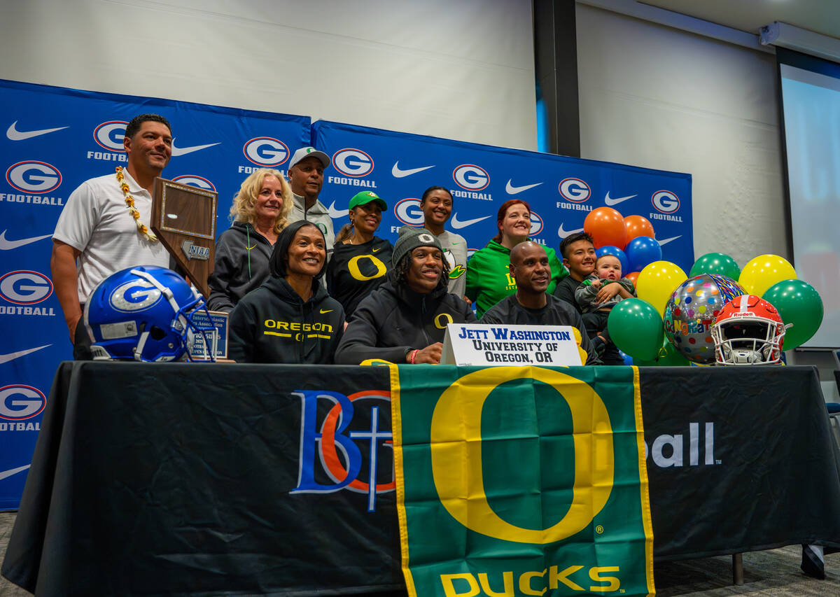 Jett Washington poses for a photo with his coach and family after signing his offer letter to p ...