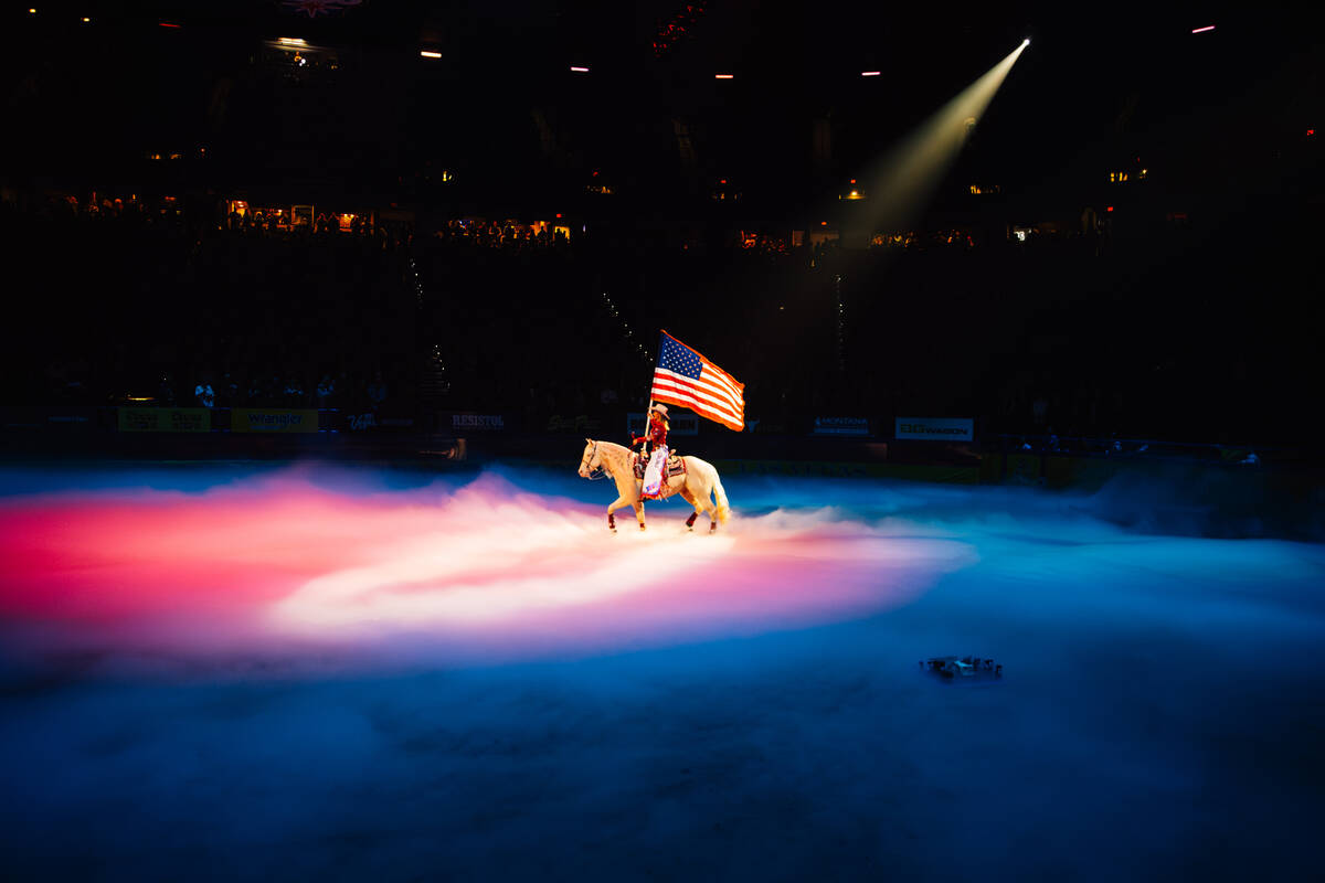 A cowgirl rides out for the national anthem on day four of the National Finals Rodeo at the Tho ...