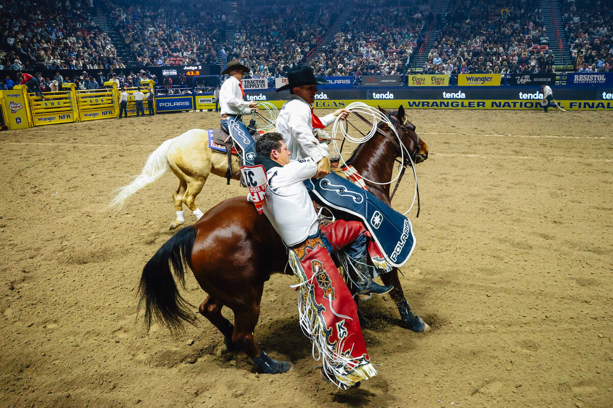 Kade Sonnier gets a hand from a pickup man on day four of the National Finals Rodeo at the Thom ...