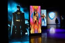 A visitor walks past portraits of DC Comics superheroes as she enters the "Action and Magic Mad ...