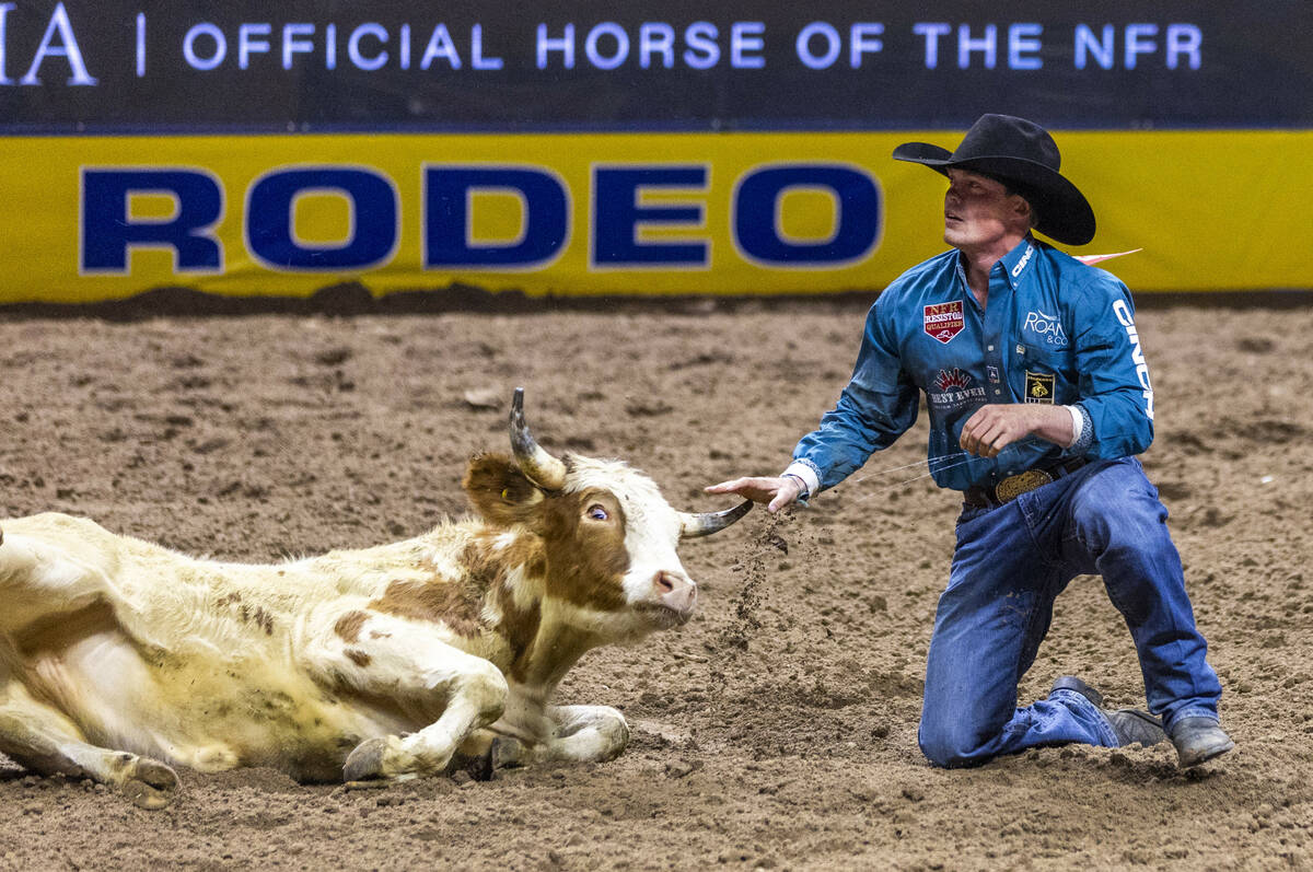 Tucker Allen sets looks up from his steer after a tying win in Steer Wrestling during Day 2 of ...